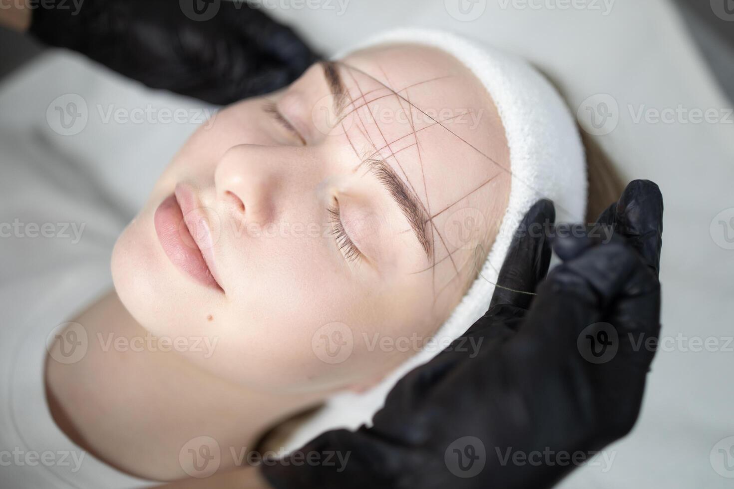 A skilled technician performs a long-lasting makeup procedure on a relaxed client in a beauty salon. The pampering experience highlights a focus on enhancing natural features. photo