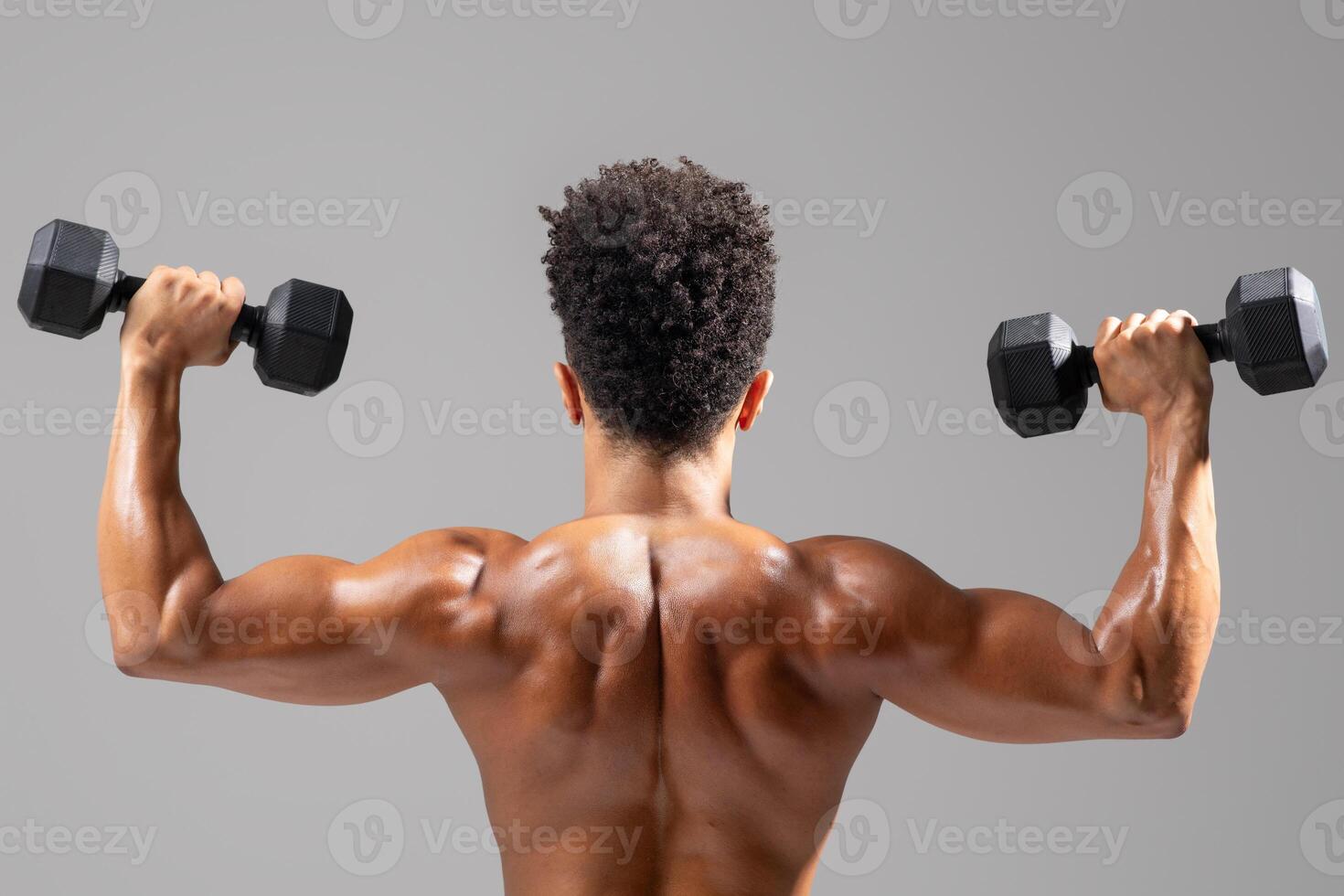 A young Brazilian man is engaged in a fitness workout, lifting dumbbells with a focus on his upper body strength. photo