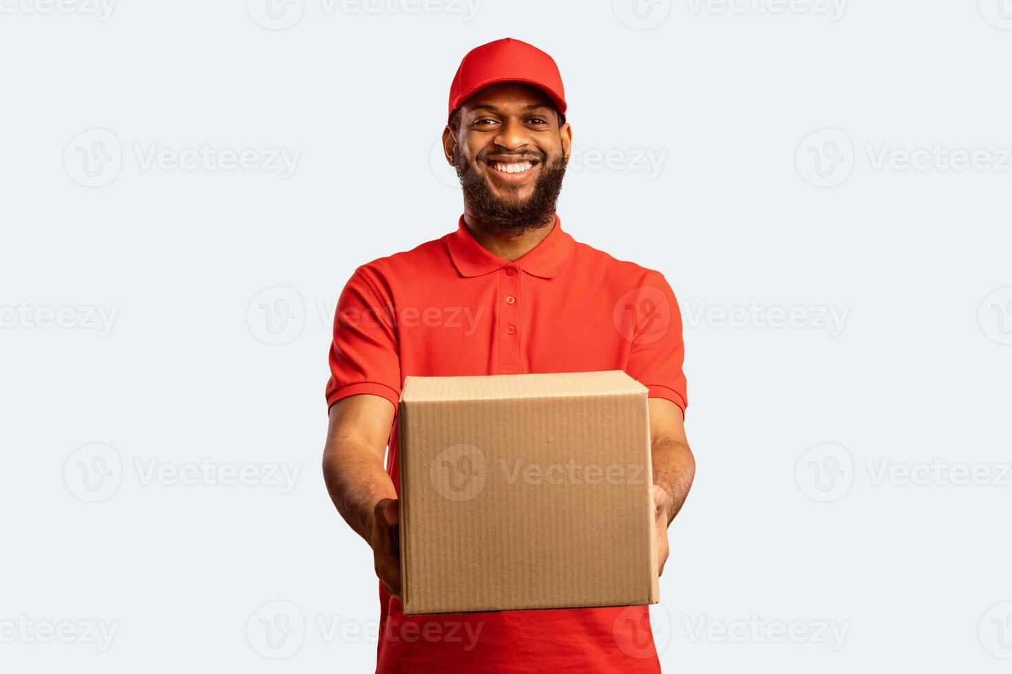 Delivery Service. African American Courier Offering Cardboard Box To Camera Over Yellow Studio Background Delivering From Online Store To Home. photo
