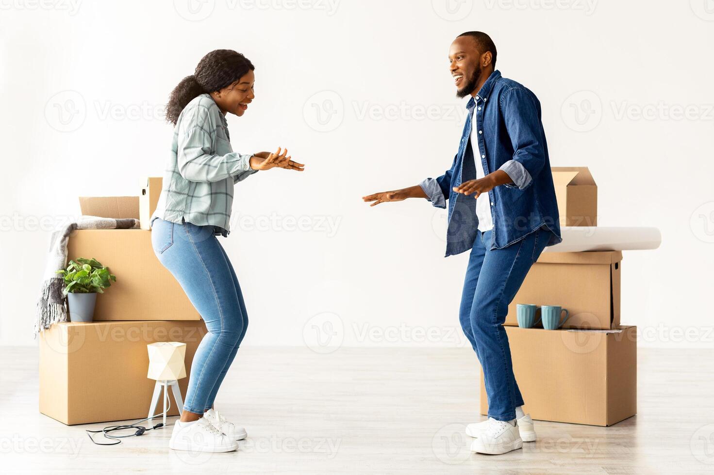 Happy Young Black Spouses Dancing In Their New Flat On Moving Day, Cheerful African American Couple Having Fun Among Cardboard Boxes With Belongings While Relocating To Own Apartment, Copy Space photo