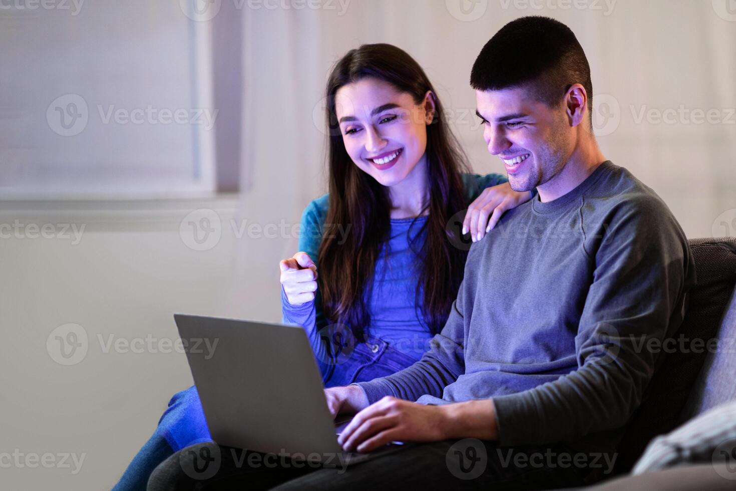 Lifestyle Concept. Happy couple with laptop spending time together at home, girl pointing at screen photo