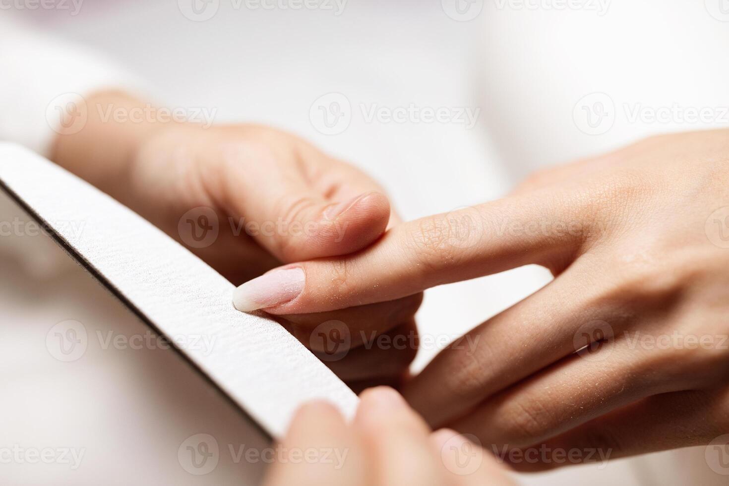 Women are pampering themselves as they receive manicures in a stylish salon. Skilled hands focus on nail care using a file to shape and enhance their appearance. photo