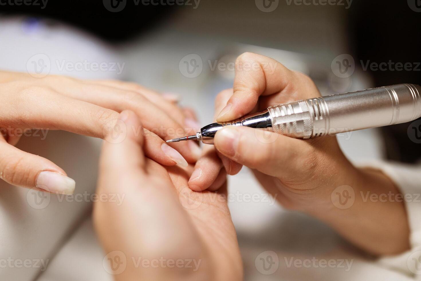 A skilled technician is carefully applying a manicure to a woman's nails in a trendy salon. The atmosphere is relaxed and focused on enhancing beauty through pampering services. photo