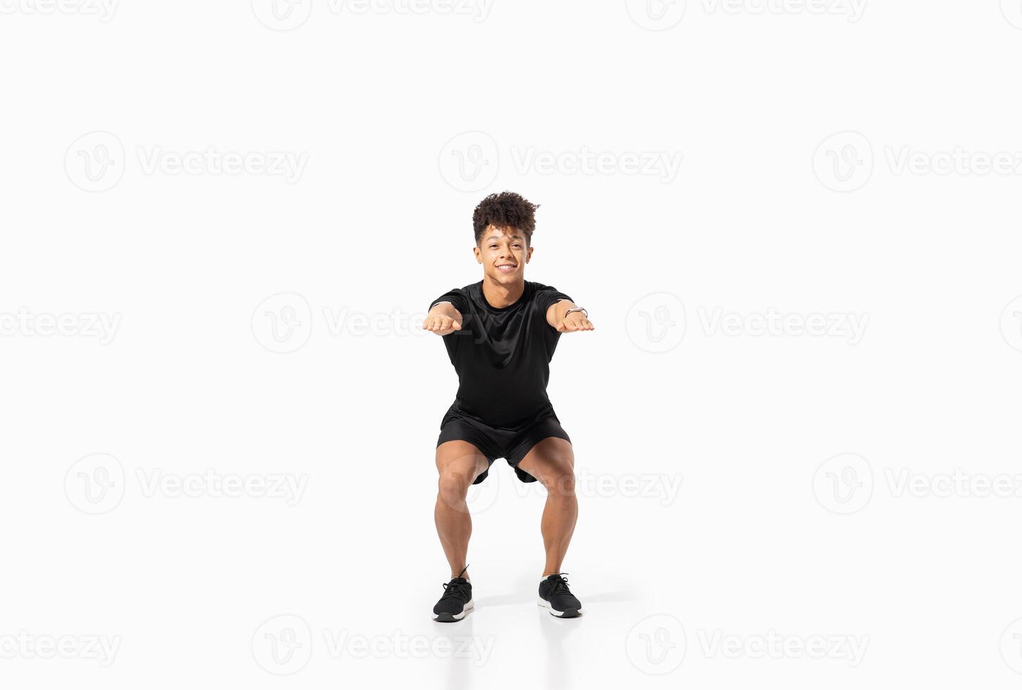 A young Brazilian man is performing a squat exercise, showcasing proper form and focus. He is dressed in athletic wear, emphasizing a commitment to fitness and a healthy lifestyle. photo