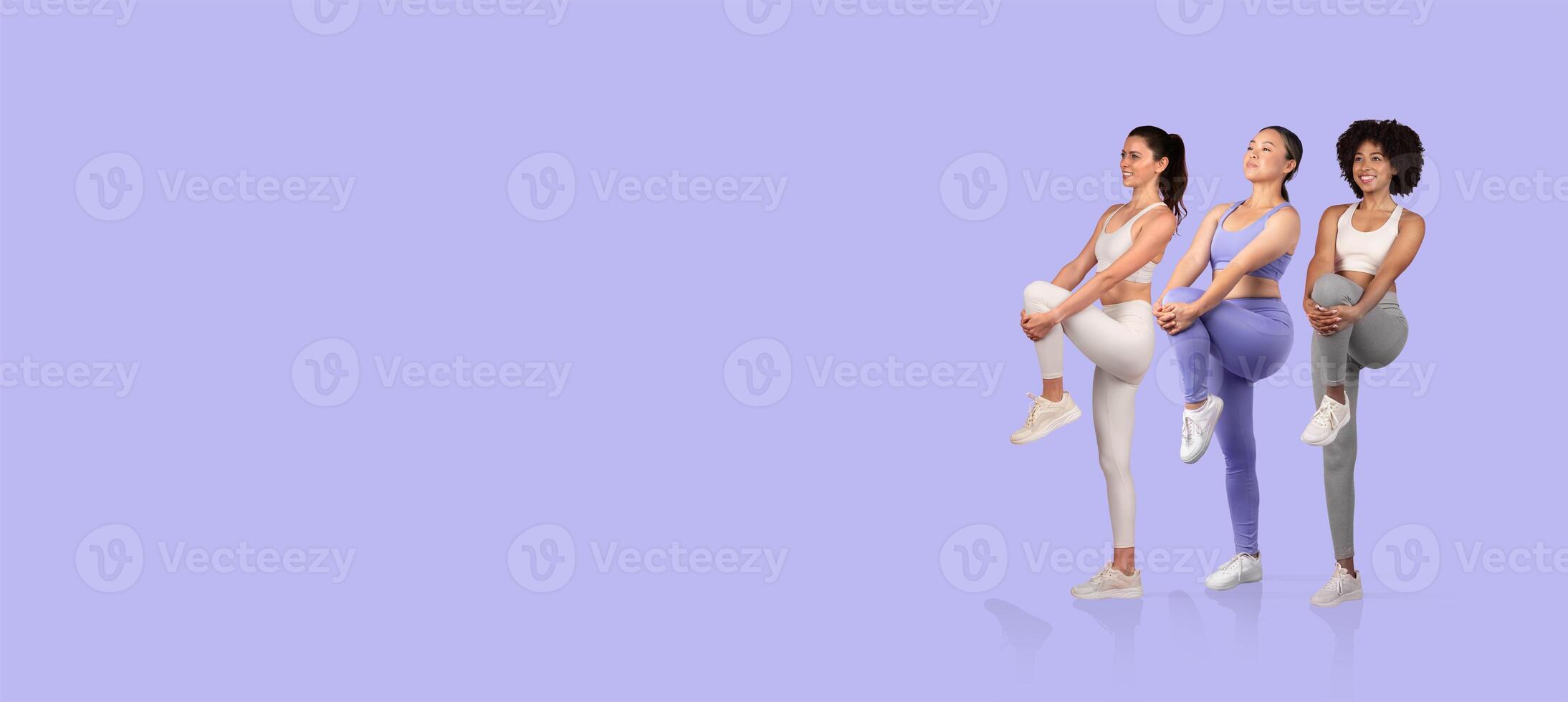 Three women are performing an exercise routine together, showcasing different athletic poses in vibrant workout clothing. They appear focused and energized during their fitness session. photo