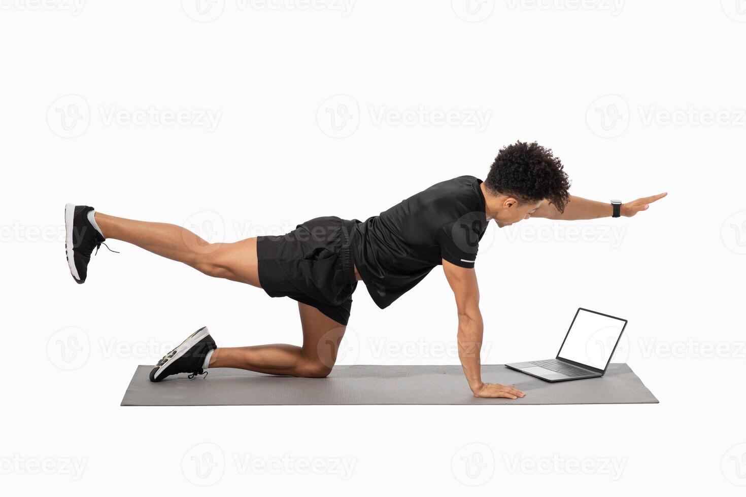 A young Brazilian man engages in an athletic workout routine at home, utilizing a laptop for guidance. He showcases a strong focus on maintaining healthy lifestyle habits. photo