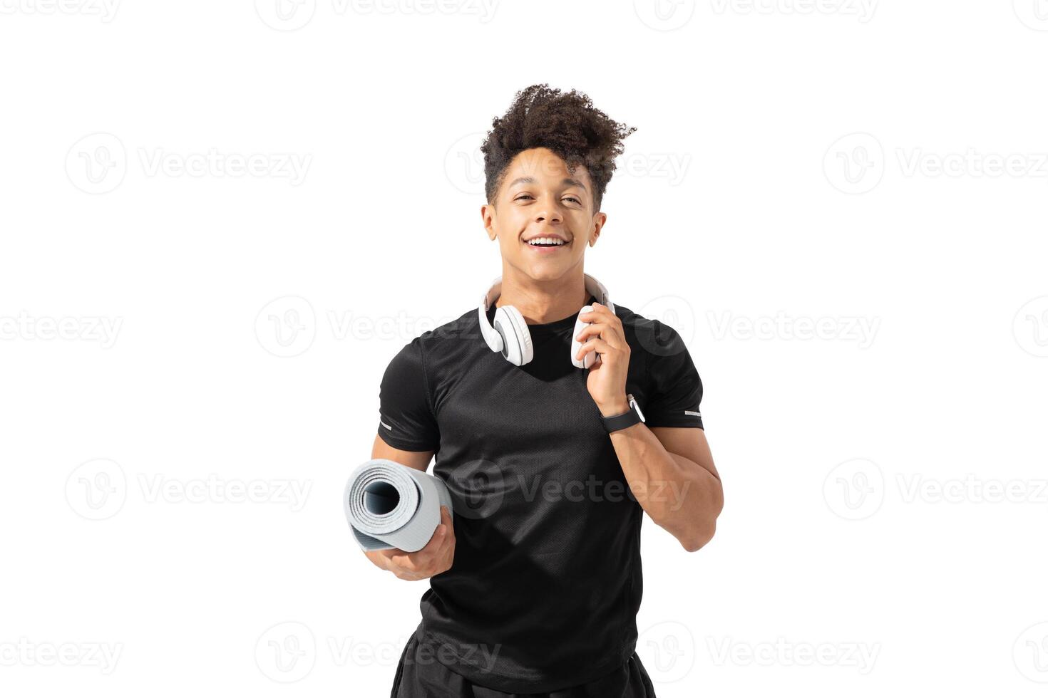 A young Brazilian man stands confidently, holding a yoga mat and wearing headphones. He is dressed in athletic gear, showcasing a healthy lifestyle and enthusiasm for fitness. photo