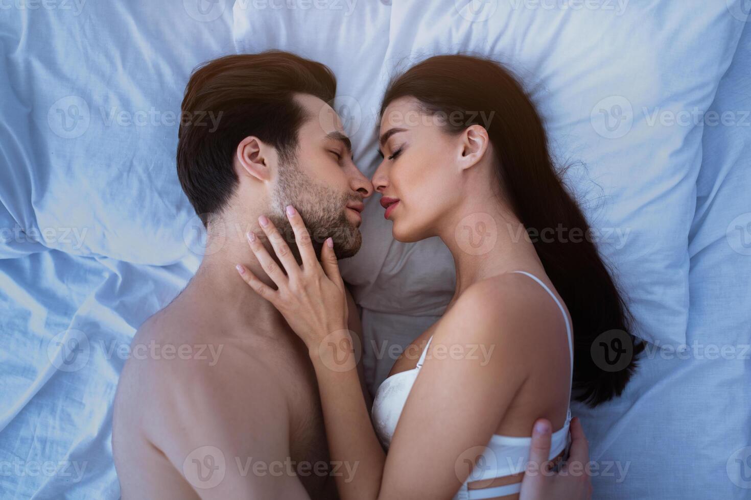 Top View Of Loving Couple Kissing Making Love Lying In Bed Indoors. Boyfriend And Girlfriend Making Sex Enjoying Intimacy Foreplay And Sensual Pleasure At Home. Shot Of Passionate Lovers photo