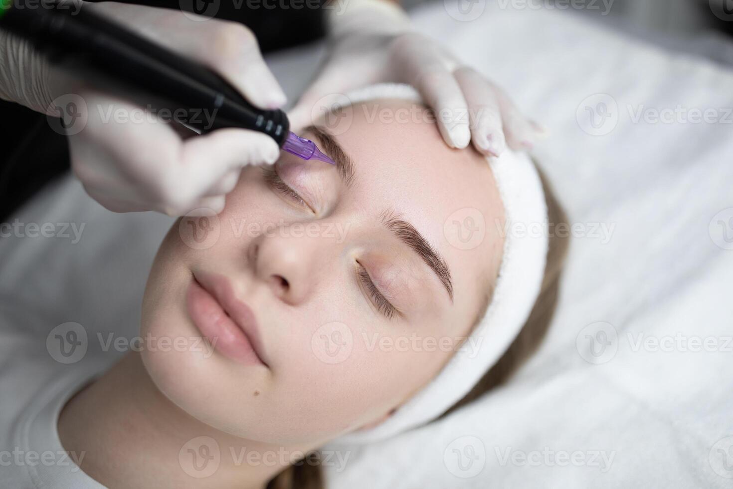 A highly skilled beauty artist applies a permanent makeup procedure to a relaxed client in a modern salon. The atmosphere is serene and focused on pampering and enhancing natural beauty. photo