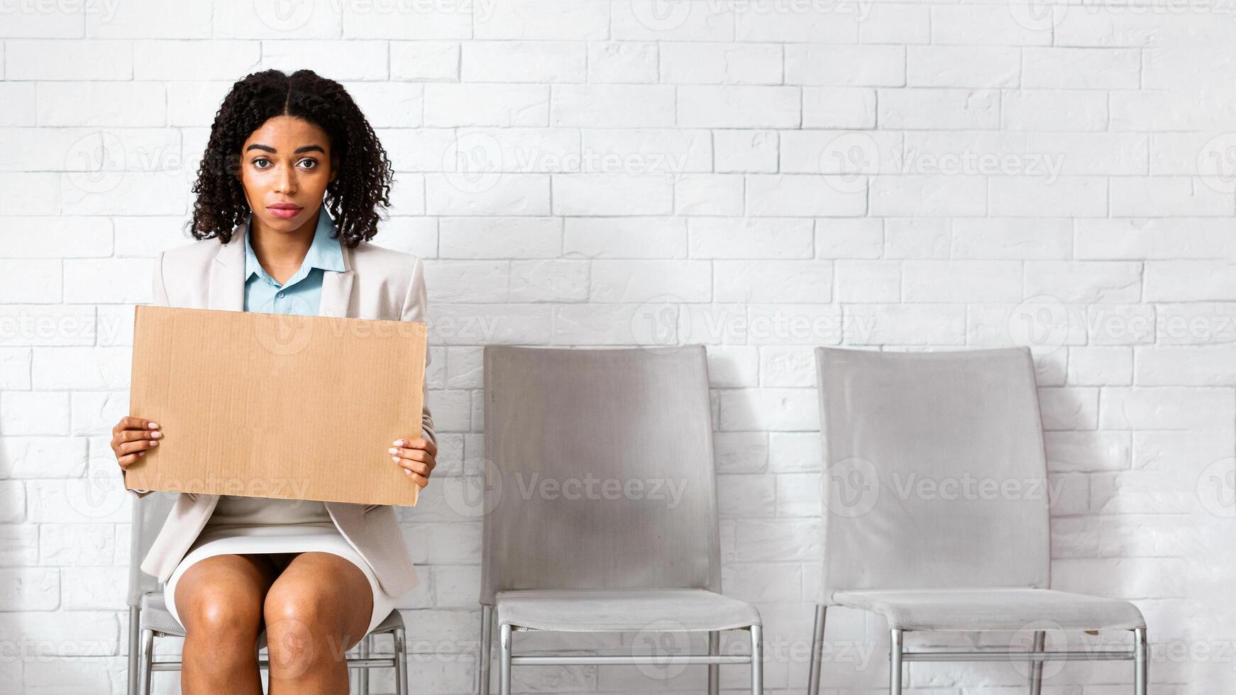 Desperate black lady holding sign I NEED WORK while waiting for employment interview at company office. Space for text photo