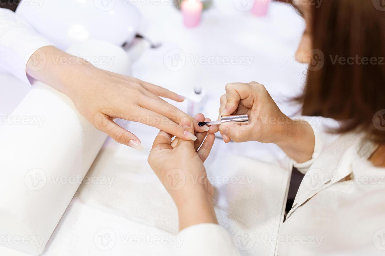 A skilled technician is applying polish to a woman's nails in a fashionable salon. The atmosphere is relaxing, with soft lighting and pampering services in focus. photo