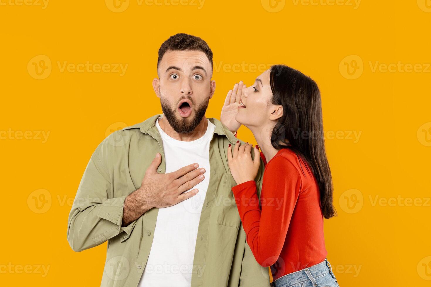 A young couple expresses affection as the woman whispers a secret to the man, who looks surprised. Their playful interaction captures the joy of intimacy in a vibrant, colorful setting. photo
