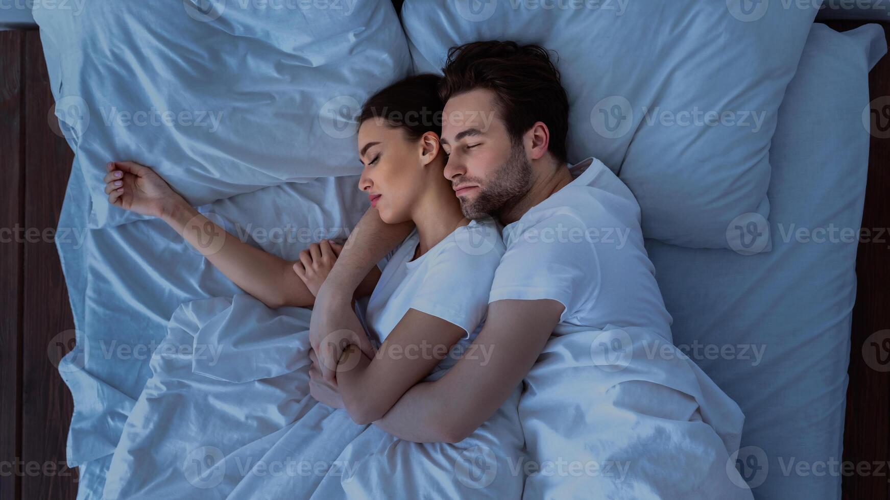Husband And Wife Hugging Sleeping Together Lying In Bed At Home, Above View Shot. Married Couple Resting In Cozy Bedroom, Embracing And Napping. Happy Marriage Concept photo