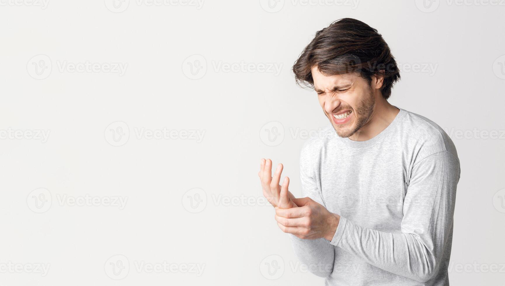 Trauma and arthritis. Man suffers from pain in his hand isolated on gray background, studio shot photo