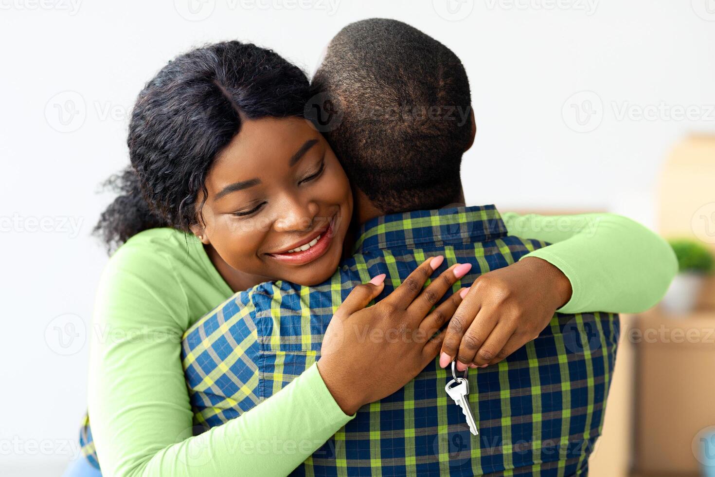 New Home. Happy black wife holding house keys and hugging husband, excited african american woman enjoying moving to new apartment together, cheerful spouses celebrating relocation, closeup photo