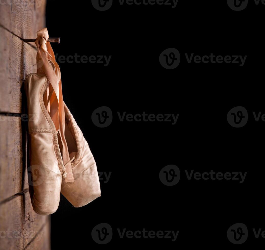 Used ballet shoes hanging on wooden background photo