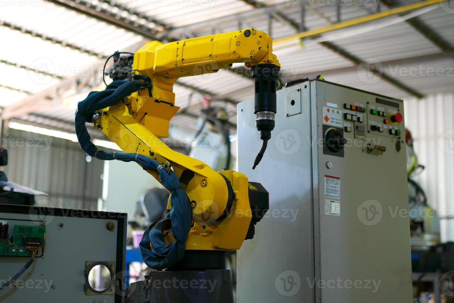 A yellow robot is standing in front of a machine photo
