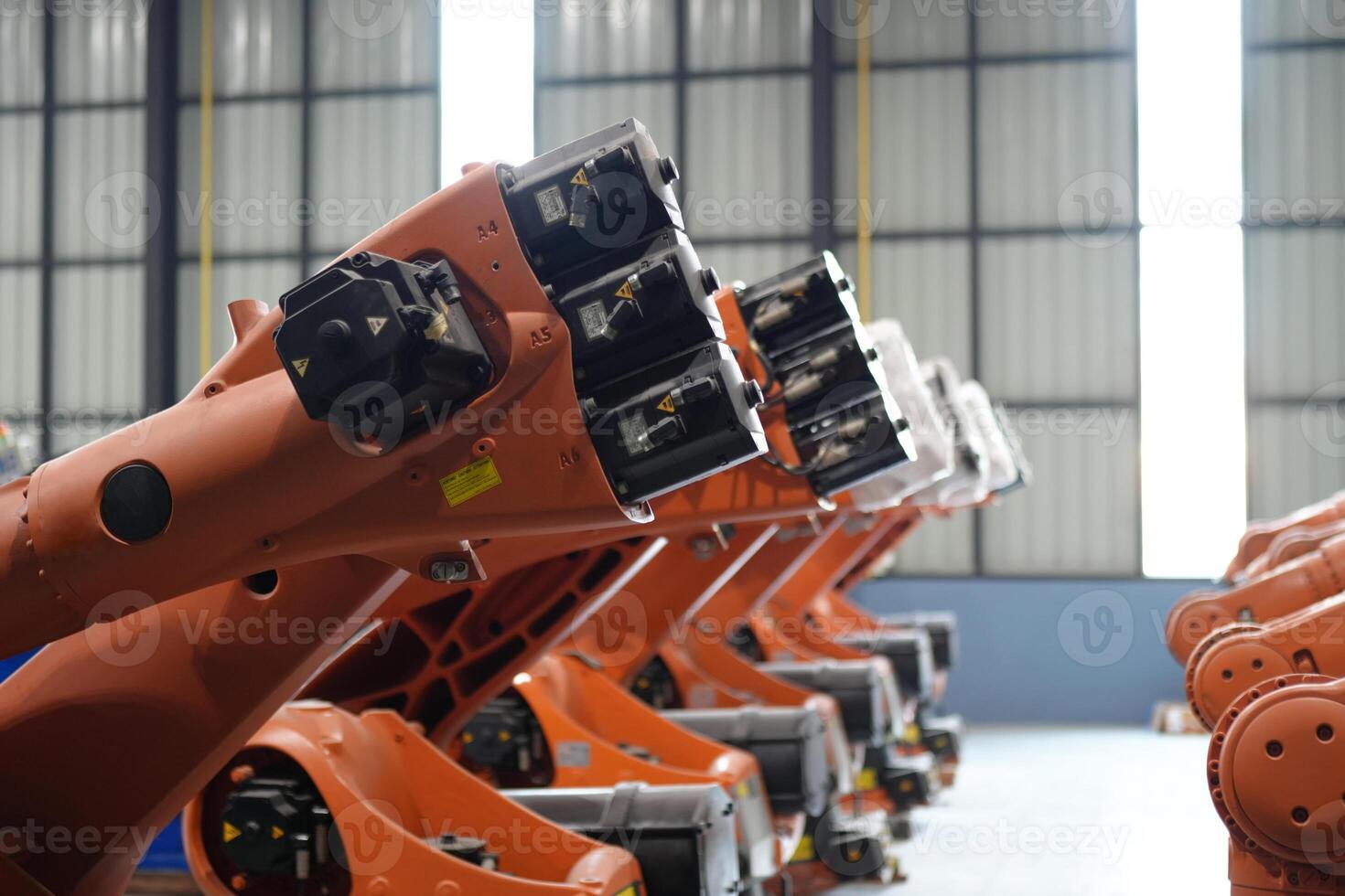A row of orange industrial robots in a factory photo