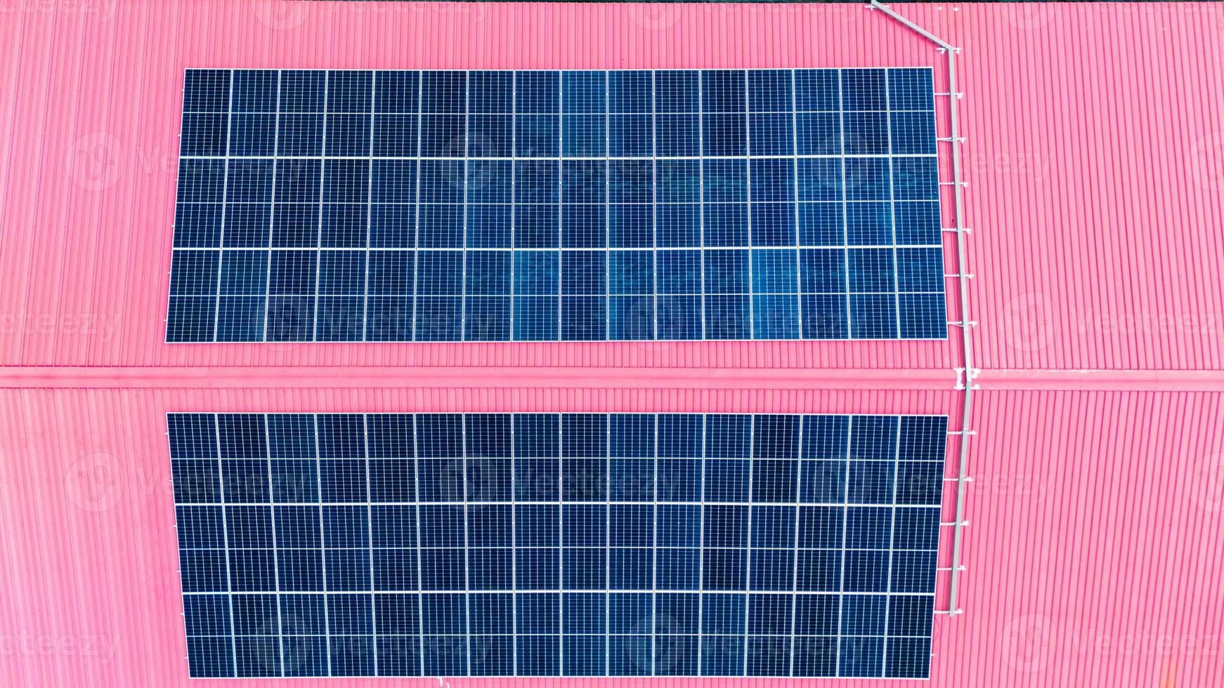 Two solar panels on a pink building photo