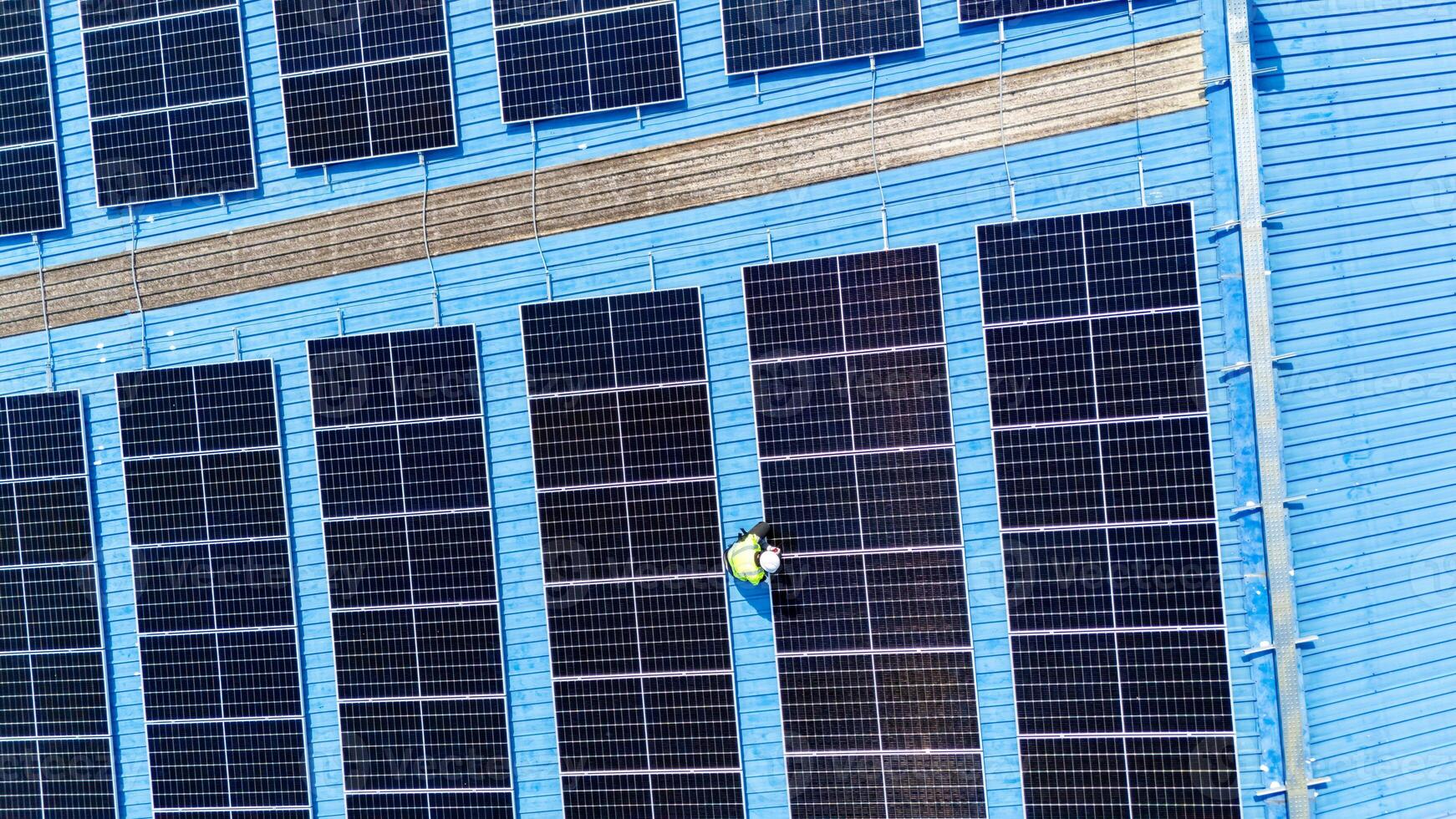 A man is standing on a ladder next to a blue building photo