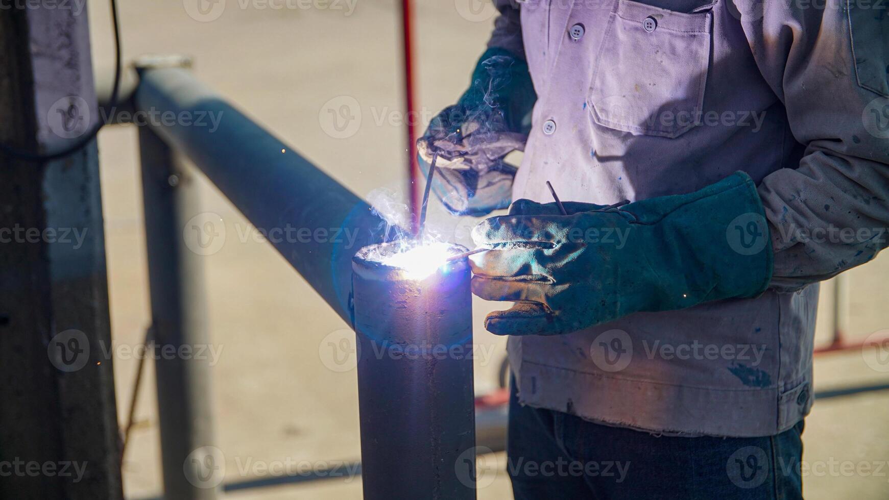 A man welding a metal pipe with a welding torch photo