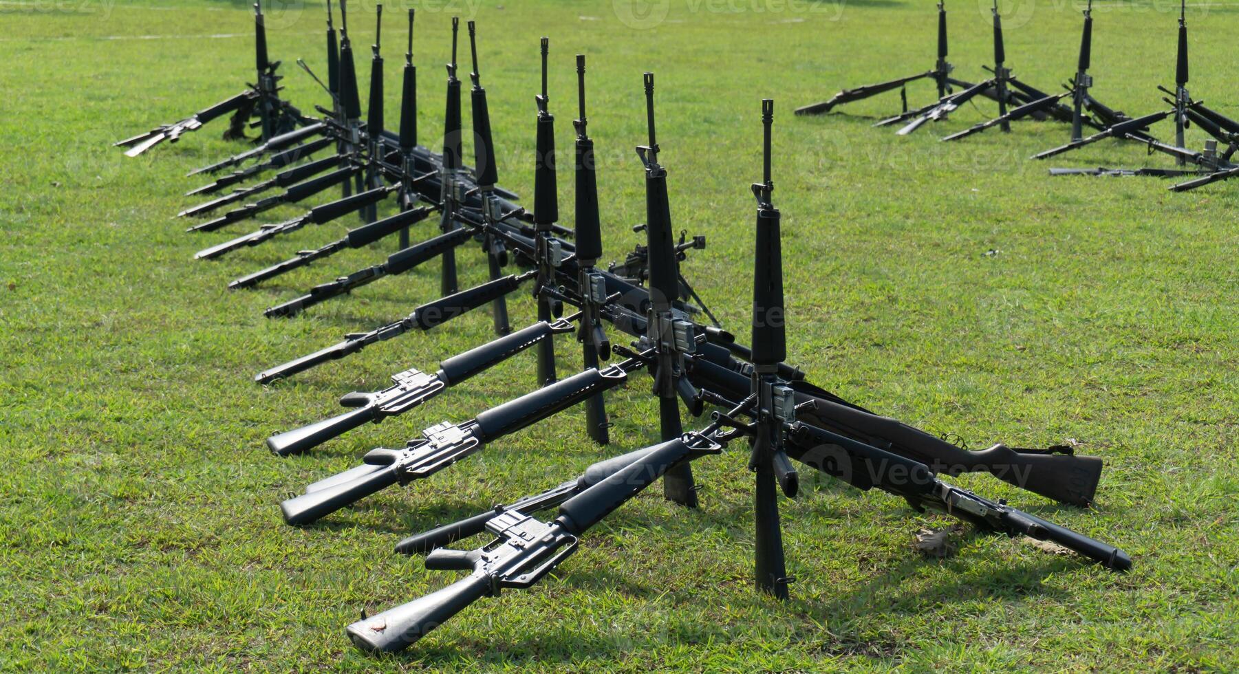 A row of guns on a grassy field photo