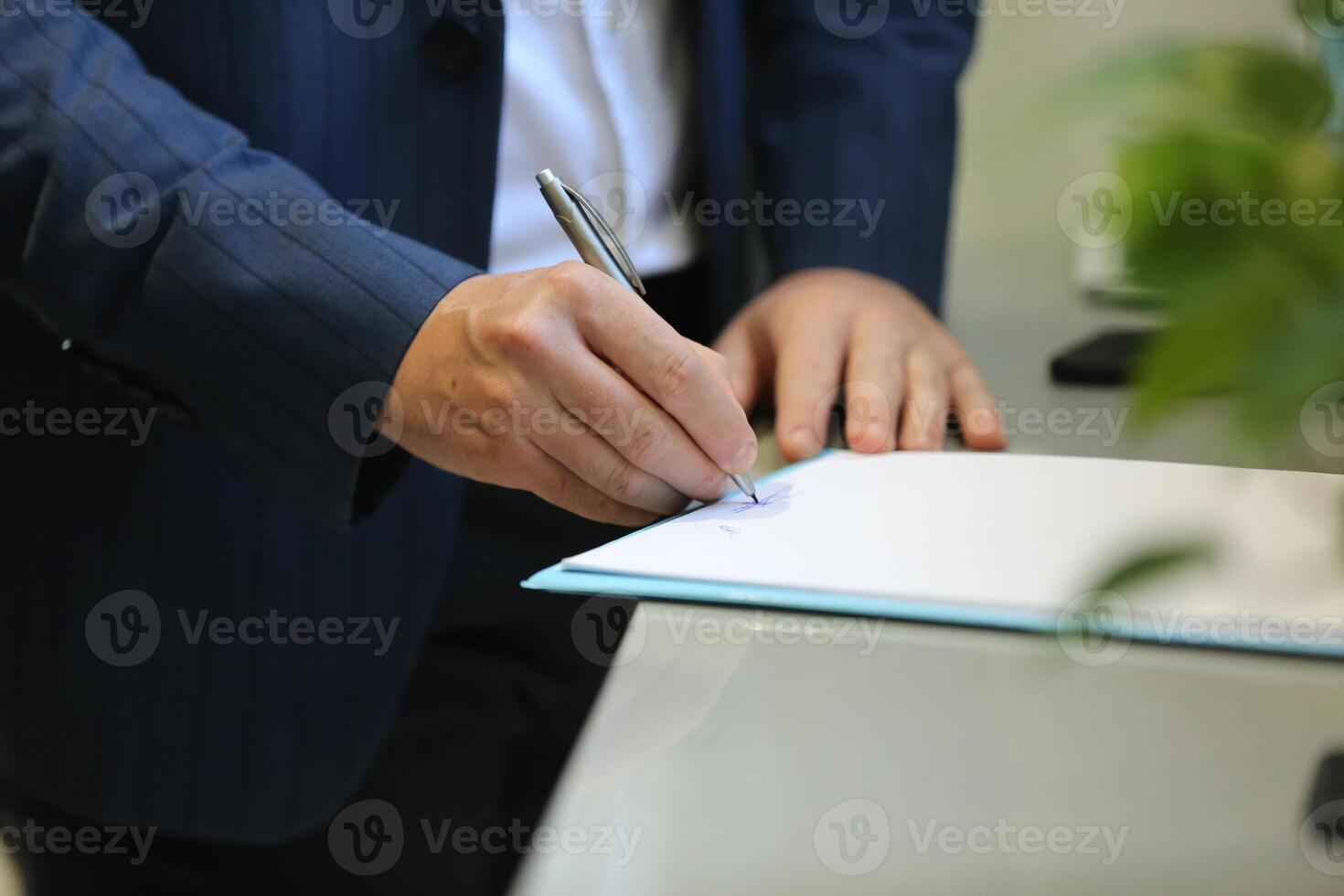 A person in a suit is signing a document photo