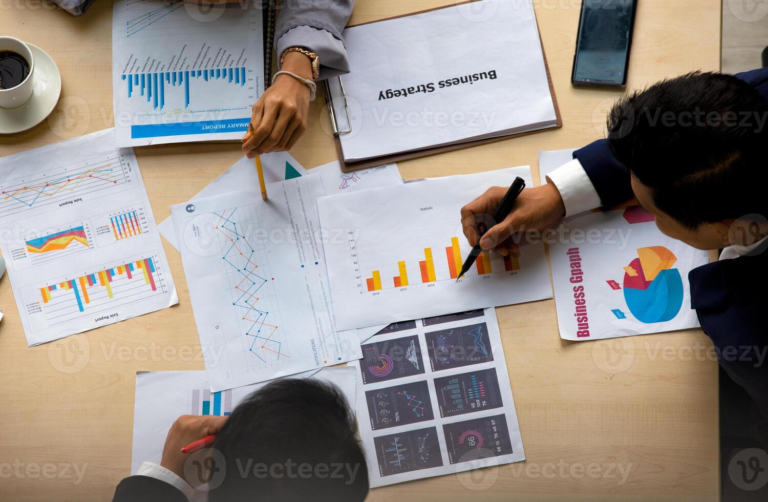 A group of people sitting around a table with papers and graphs photo