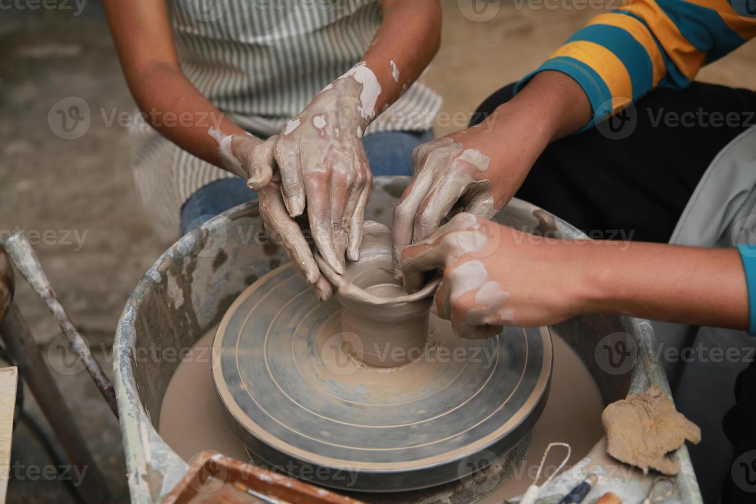 Two people are making pottery on a potter's wheel photo