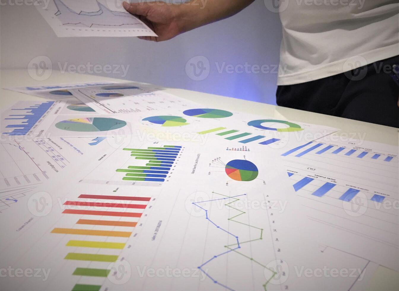 A man is looking at graphs and papers on a table photo