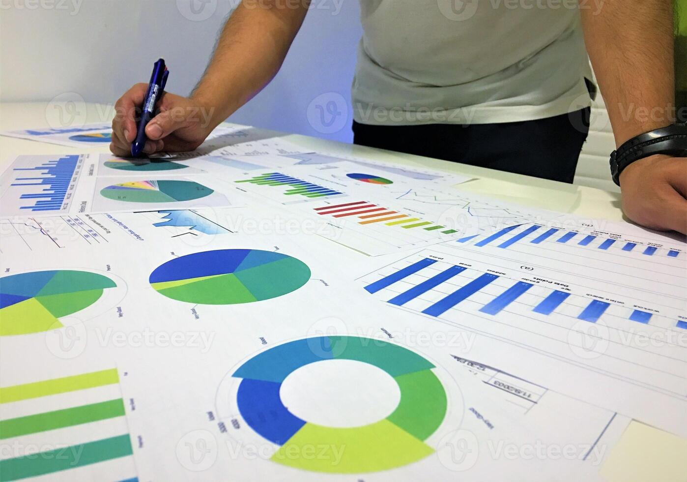 A man is working on a table with graphs and charts photo