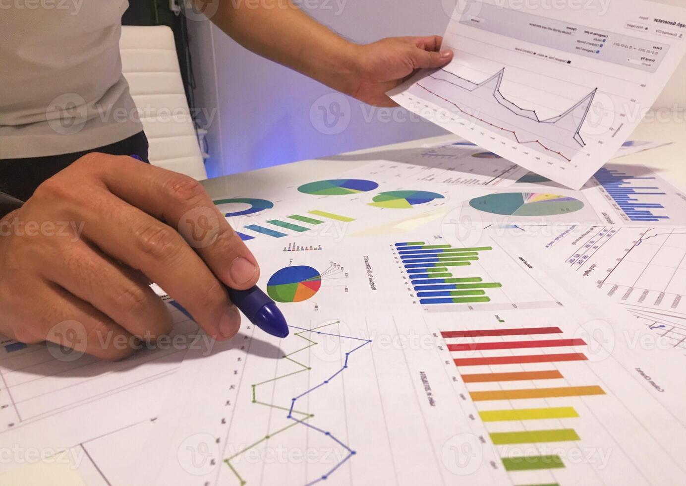 A person is holding a pen and looking at graphs photo