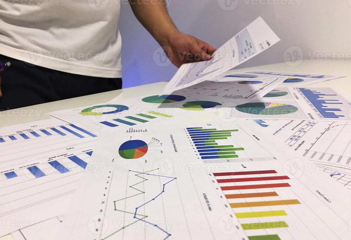 A man is looking at graphs and papers on a table photo