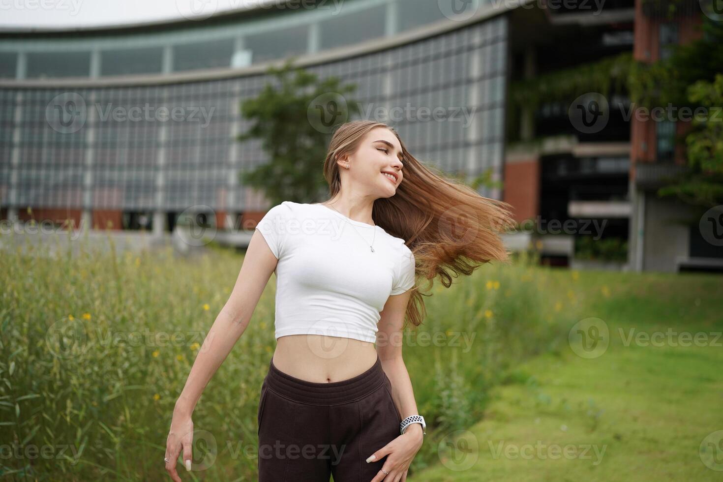 A woman in a crop top and pants standing in a field photo