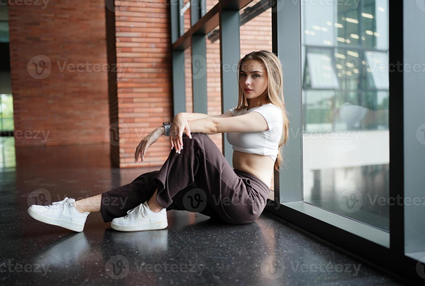 A woman sitting on the floor near a window photo