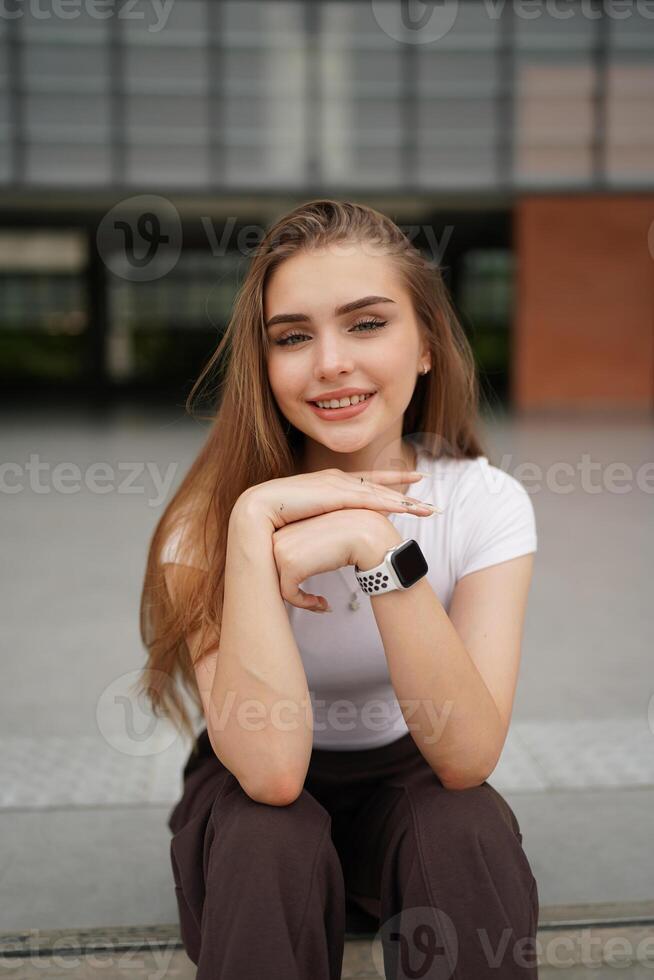 A young woman sitting on the ground with her wrist watch on photo