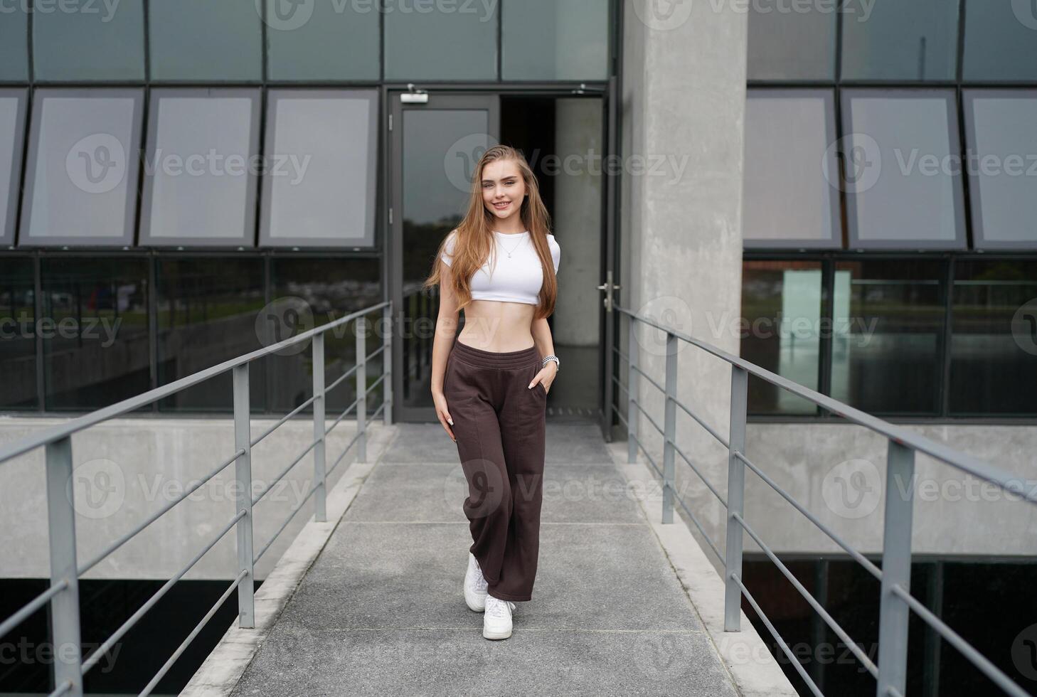 A woman in a white top and brown pants standing on a bridge photo