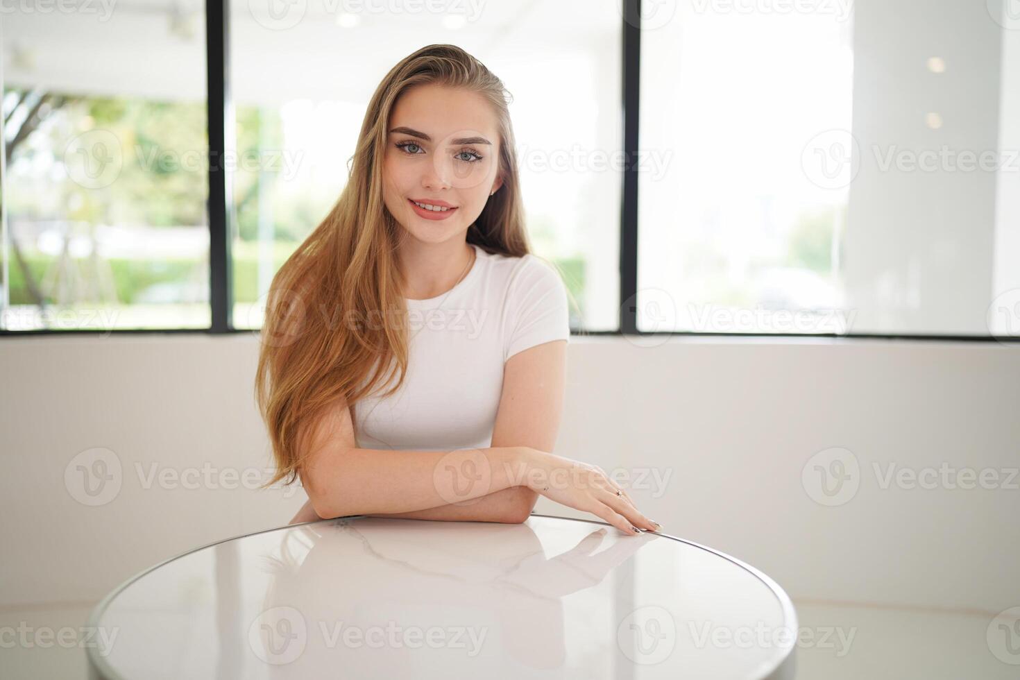 A woman sitting at a table in front of a window photo
