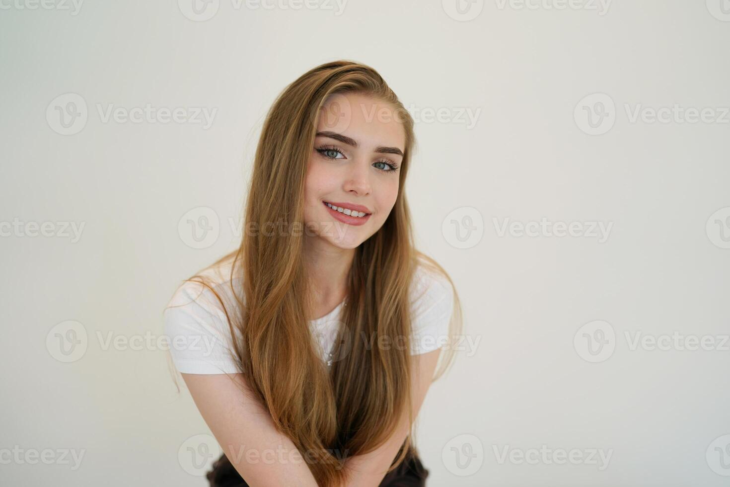 A young woman with long hair sitting on a white background photo