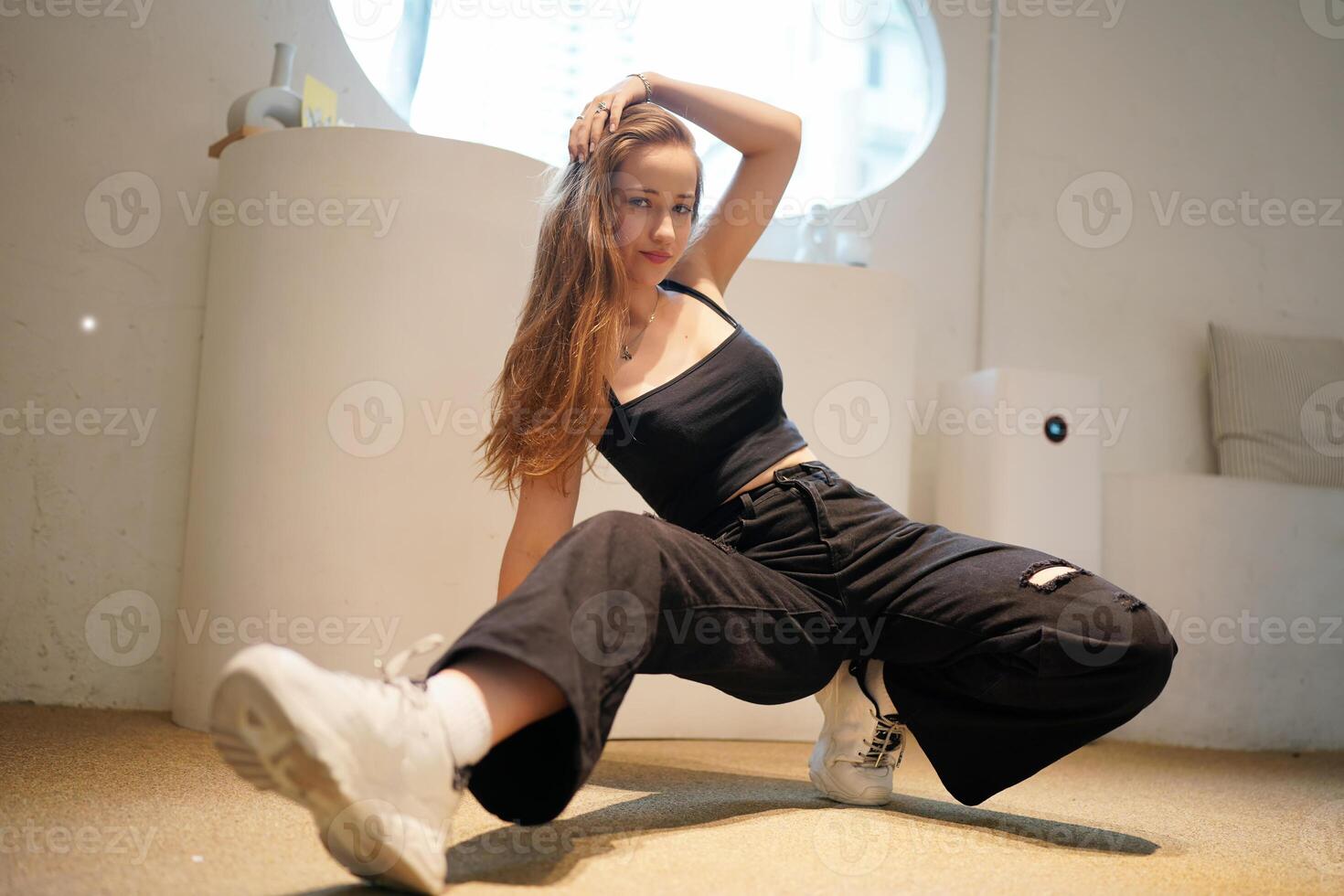 A woman in black pants and a top is doing a dance photo