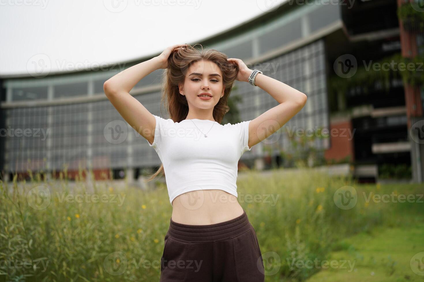 A woman in a white shirt and black pants standing in front of a building photo