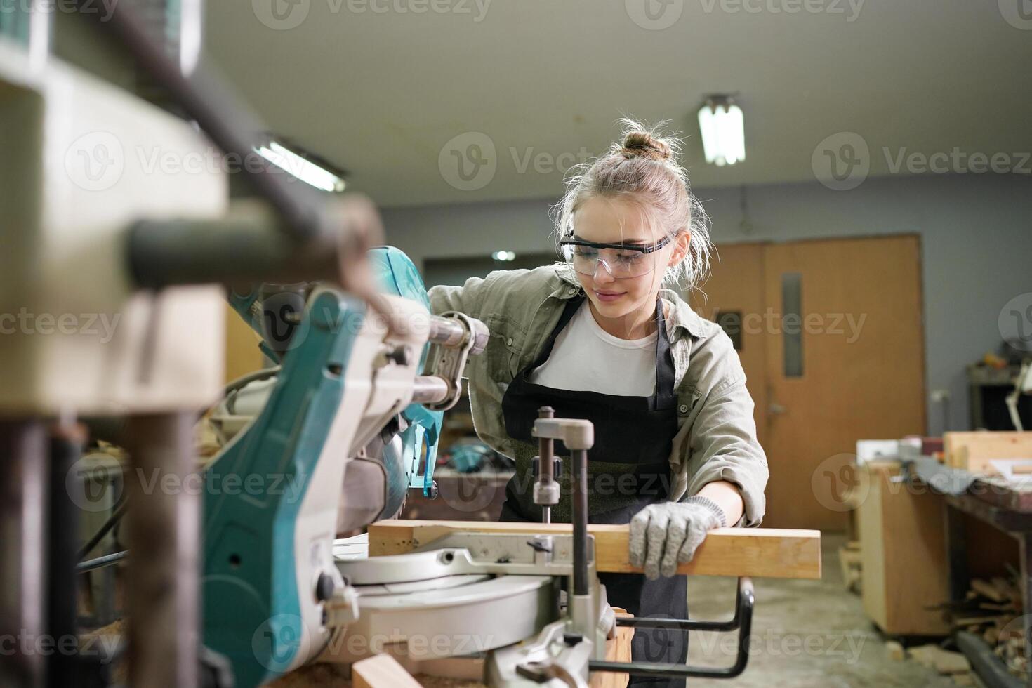 A woman in a workshop using a circular saw photo