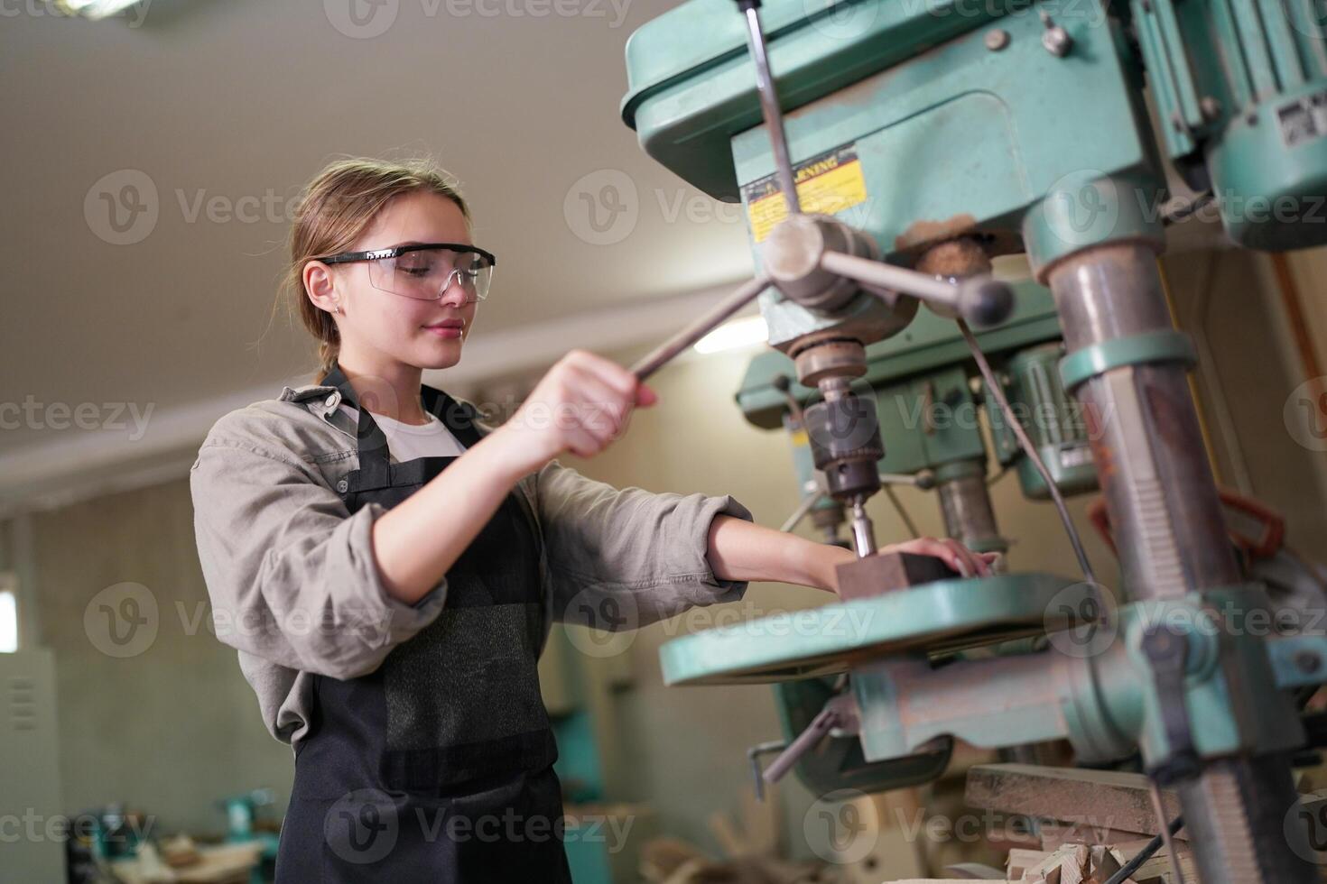 A woman in a black apron is working on a machine photo