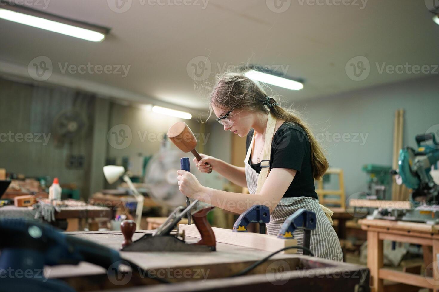 A woman is working on a wooden table with a hammer photo