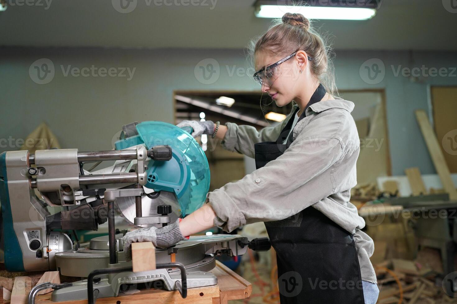 A woman in an apron is using a circular saw photo
