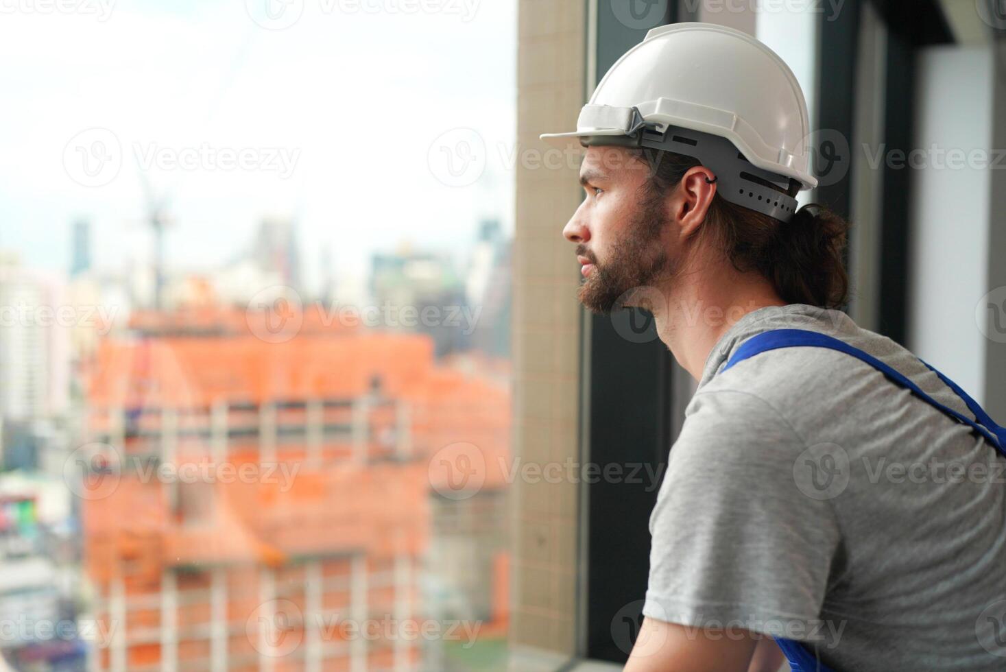 A man in a hard hat looking out a window photo