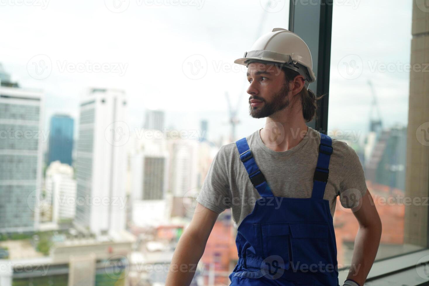 A man in overalls standing in front of a window photo
