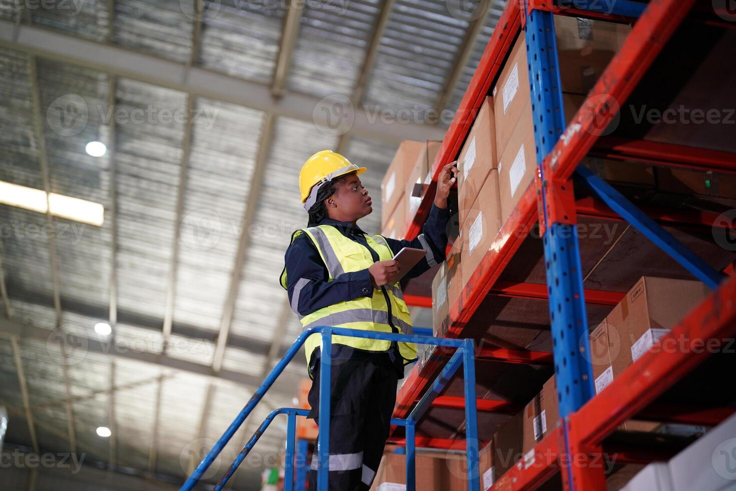 A worker in a warehouse is standing on a ladder photo