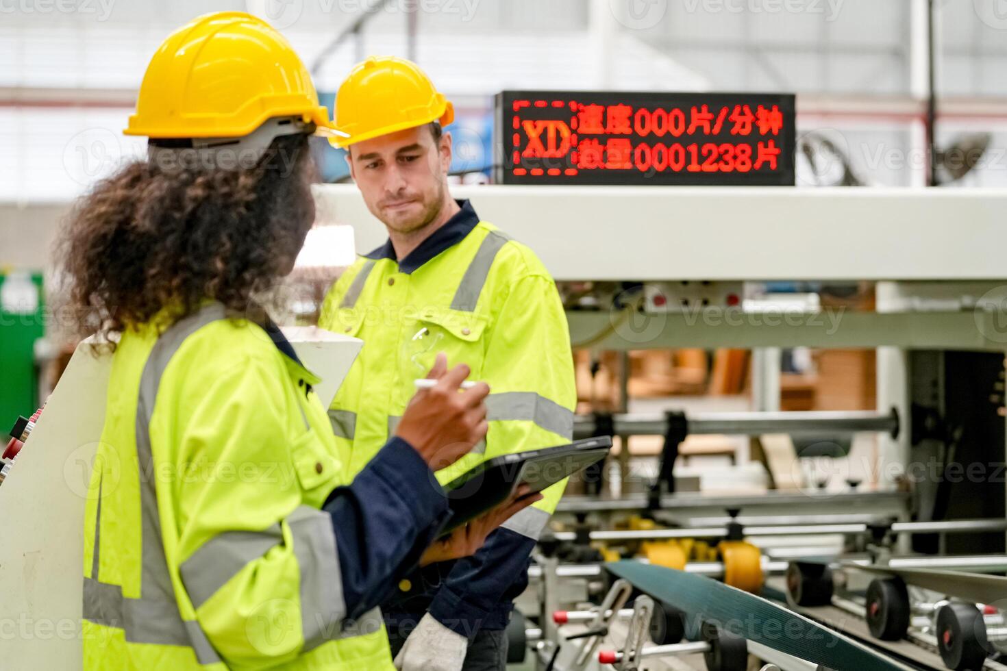 Two workers in hard hats standing in front of a machine photo