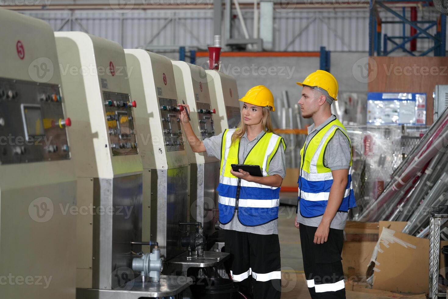 Two workers in safety vests standing next to a machine photo